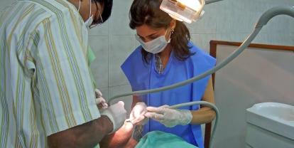 Projects Abroad volunteer assists a local dentist as he performs a check up on a patient in India. Dentistry volunteer and dentist do a routine oral checkup on a patient in India.